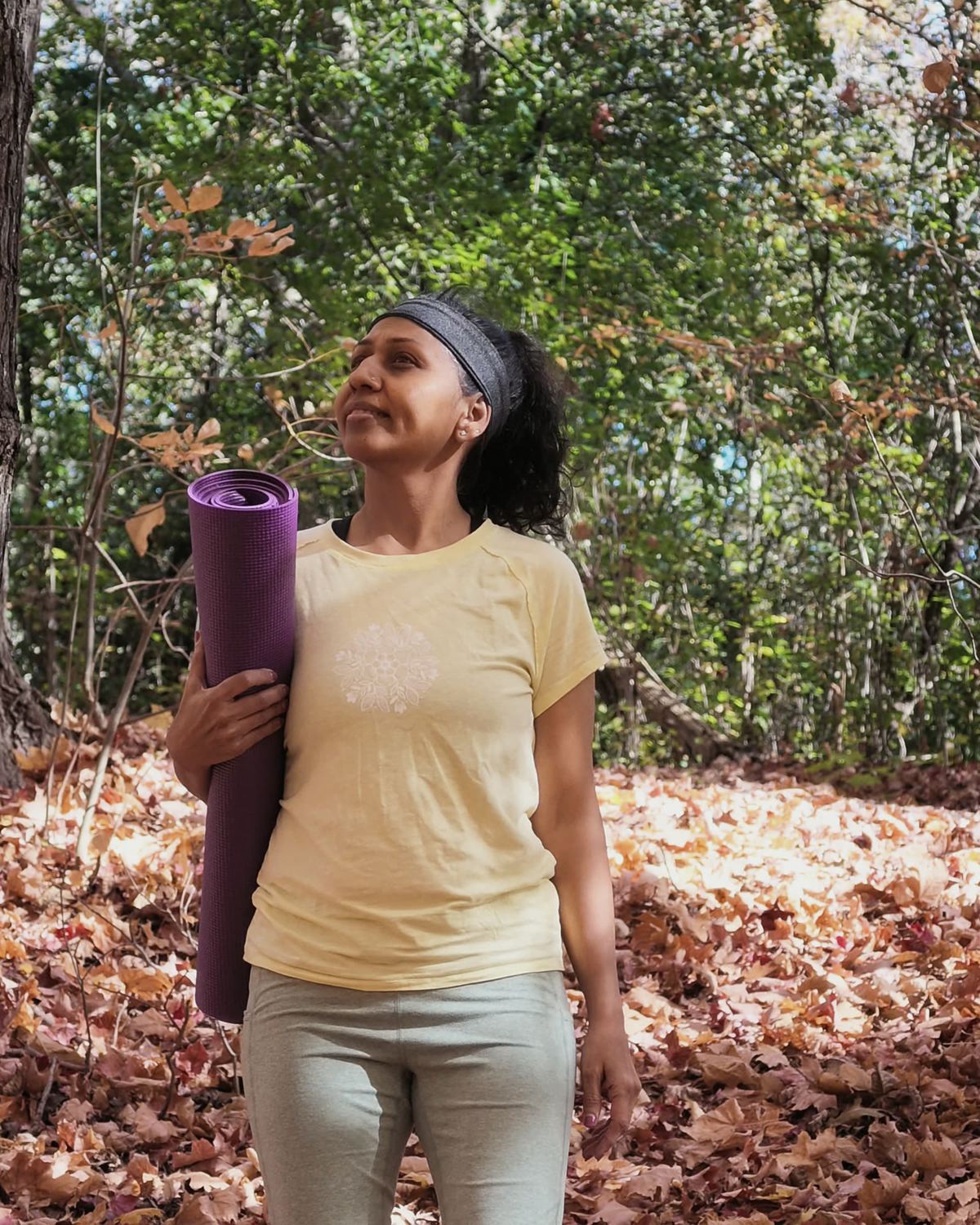 Sneh Lata carrying a rolled yoga mat, looking up